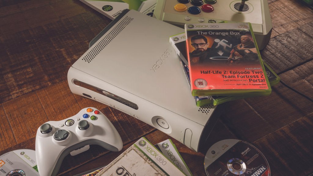 Best Xbox 360 games: a screenshot of an Xbox 360 console next to a controller and a collection of games.